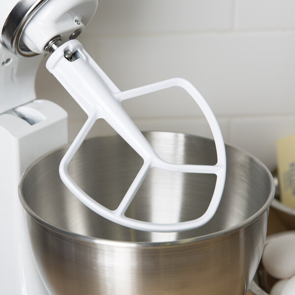 A white KitchenAid stand mixer with a coated flat beater in a bowl.