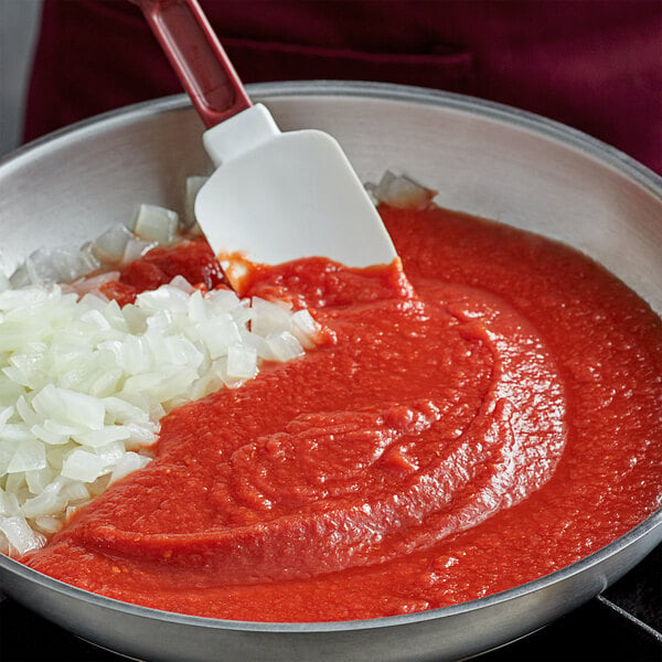 A pan of tomato sauce and onions with a spatula in it.