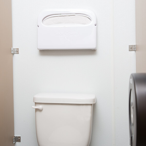 A Thunder Group toilet seat cover dispenser on a wall above a toilet.