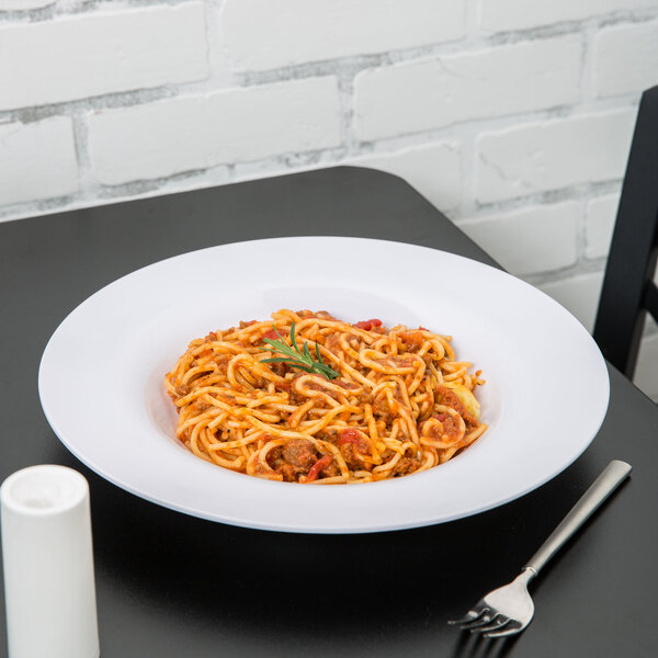 A Carlisle white melamine pasta bowl filled with spaghetti and sauce with a fork on the table.