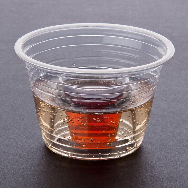 A Disposabomb clear plastic cup filled with brown liquid.