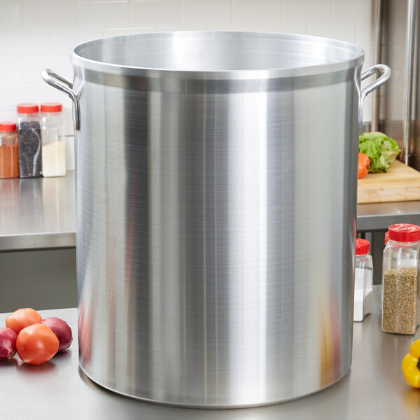 A large silver Vollrath Wear-Ever aluminum stock pot on a counter with vegetables.