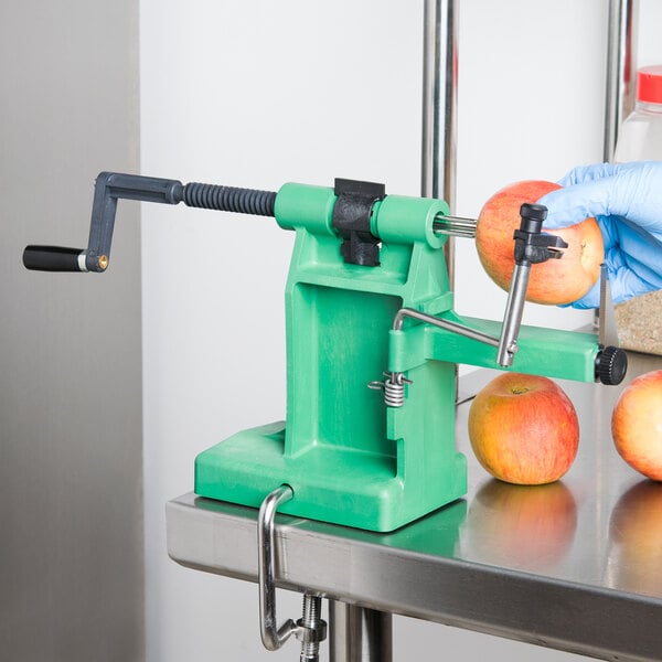 A person in a blue glove using a Matfer Bourgeat apple peeler to peel an apple.