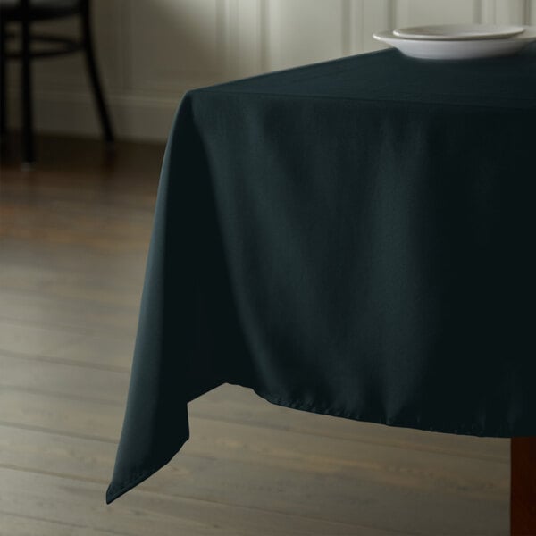 A table with a hunter green Intedge square tablecloth on it.