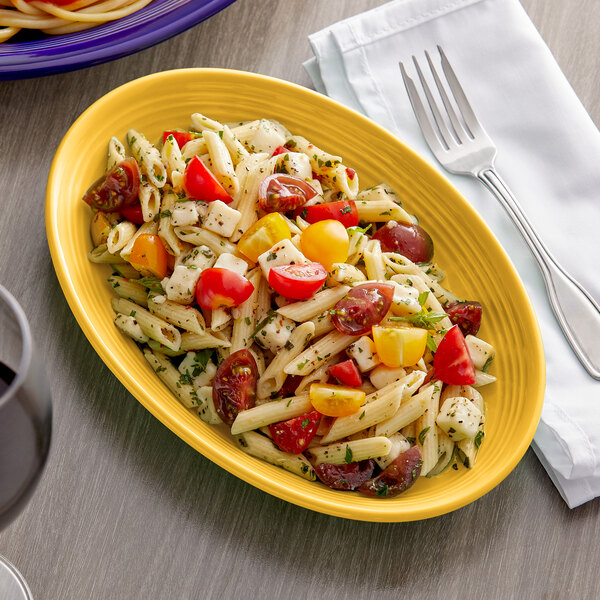 A Tuxton saffron oval china platter with pasta, tomatoes, and cheese on it.
