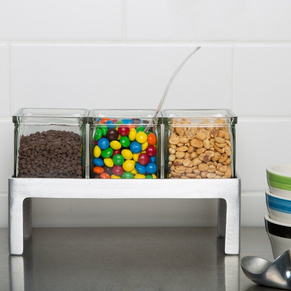 An aluminum display with three glass jars filled with different colored candies.