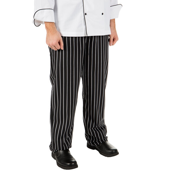 A person in a Mercer Culinary black and white striped chef pants at a professional kitchen counter.