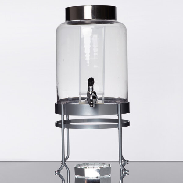 A Cal-Mil glass beverage dispenser with a silver metal stand on a table.