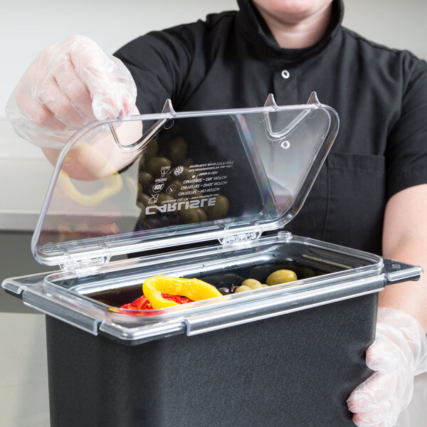 A person in gloves using a Carlisle Clear Polycarbonate Food Pan Lid to cover a container of food.