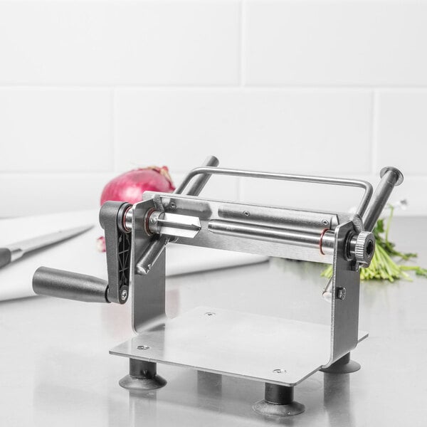 A Bron Coucke stainless steel vegetable slicer on a counter with sliced vegetables.