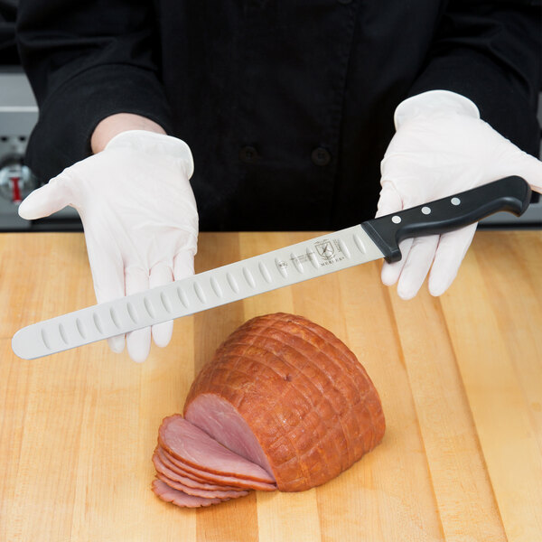 A person in white gloves using a Mercer Culinary Renaissance Slicer to cut ham.