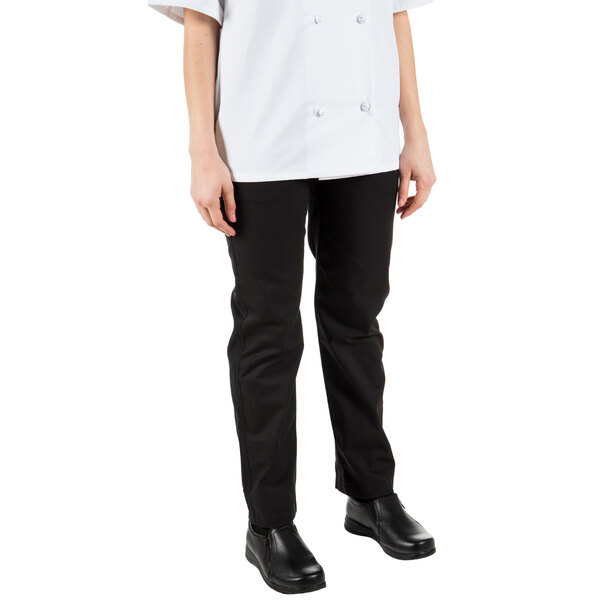 A woman wearing Mercer Culinary black pleated chef trousers.