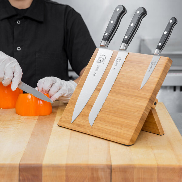 A Mercer Culinary Renaissance knife on a bamboo knife board.