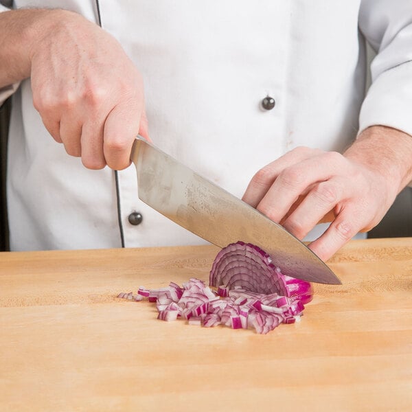 A Mercer Culinary Z&#252;M&#174; chef knife cutting a red onion on a wooden cutting board.