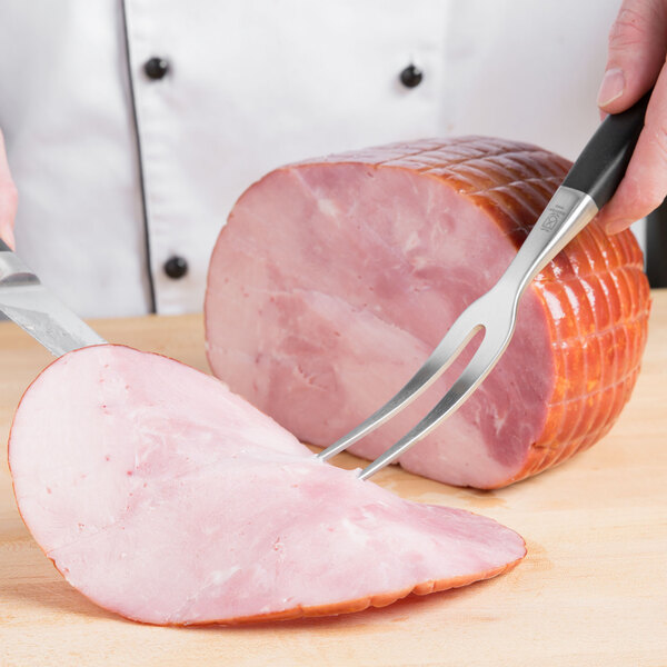 A Mercer Culinary Z&#252;M&#174; forged meat fork being used to cut meat.