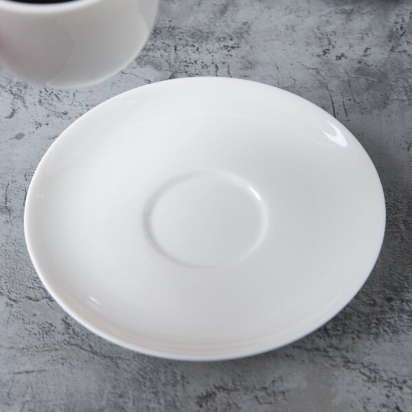 A white Reserve by Libbey bone china saucer with a white cup on a marbled surface.