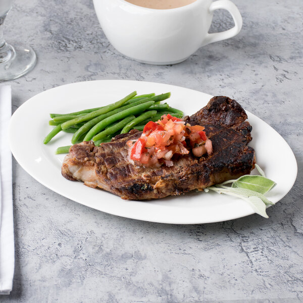 A Reserve by Libbey bone china oval platter with steak, green beans, and tomatoes.