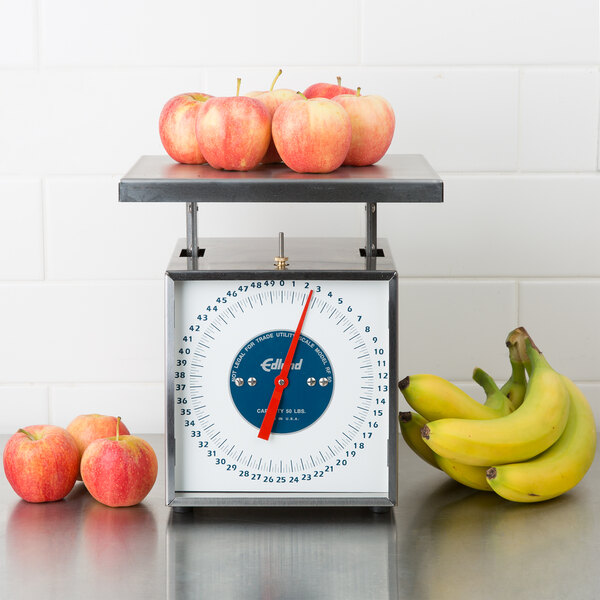 An Edlund RF-50 portion scale on a counter with apples and bananas on it.