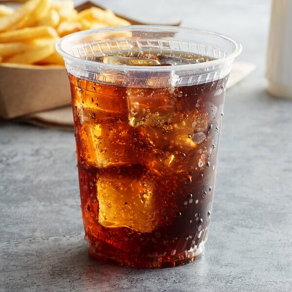 A plastic cup with ice and a drink on a table in a fast food restaurant.