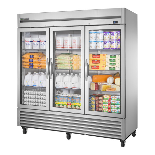 A True 3 section glass door reach-in refrigerator filled with a variety of products.