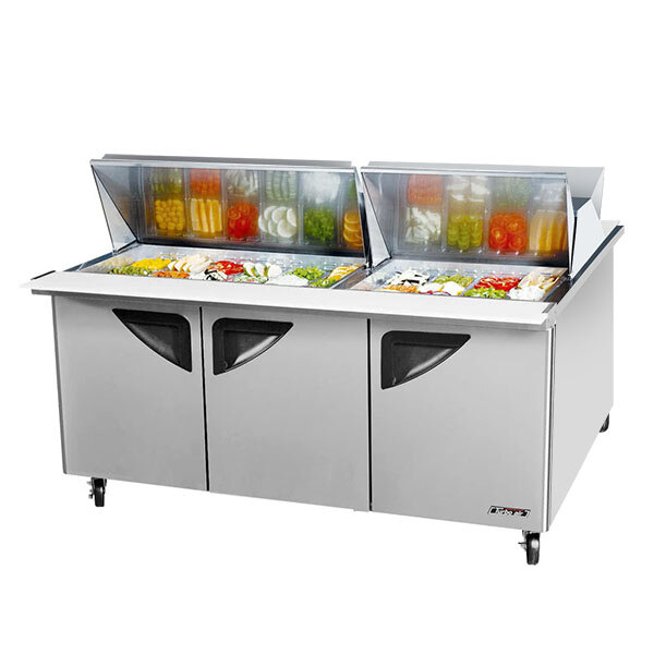 A Turbo Air dual sided refrigerated sandwich prep table with food in containers on a salad bar.