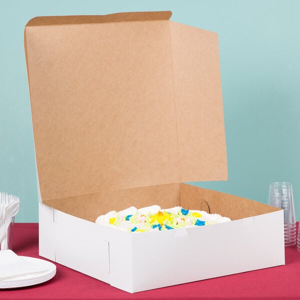A white cake in a white 16" x 16" x 5" cardboard bakery box.