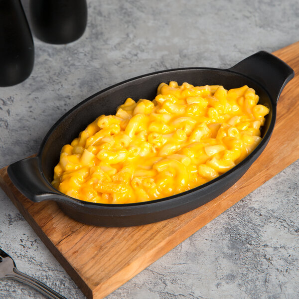A black oval faux cast iron skillet with macaroni and cheese.