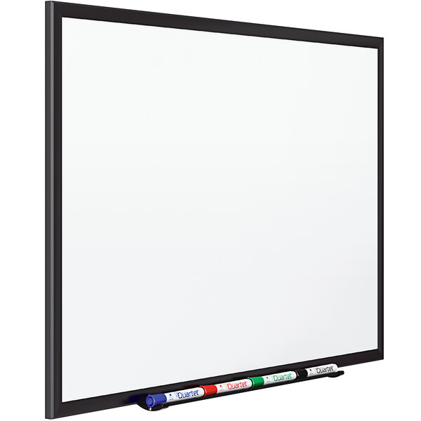 A white Quartet dry erase board with a marker on it.