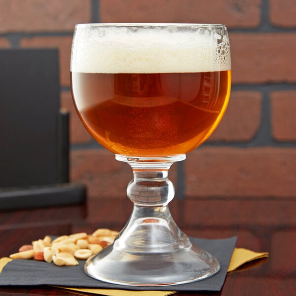 A Libbey Schooner Glass of beer with foam on top on a table.
