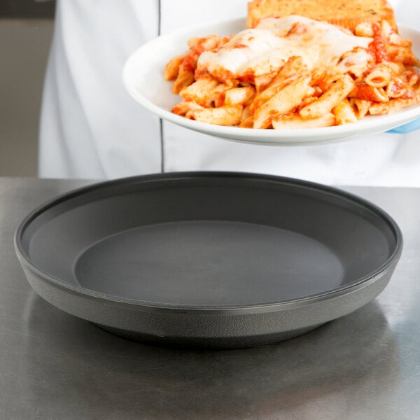 A person holding a Dinex Onyx insulated meal delivery base with a plate of pasta and cheese.