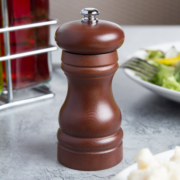 A Fletchers' Mill walnut stained wooden pepper mill on a table.