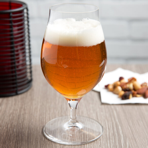 A Spiegelau stemmed beer glass full of beer on a table.