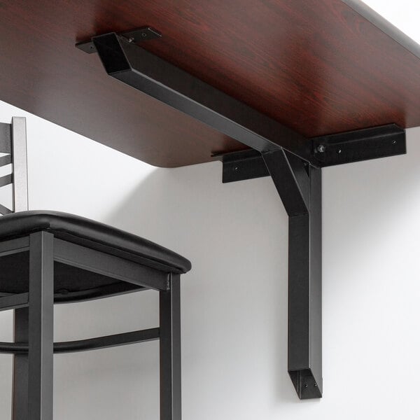 A black metal table bracket with a table and a black chair.