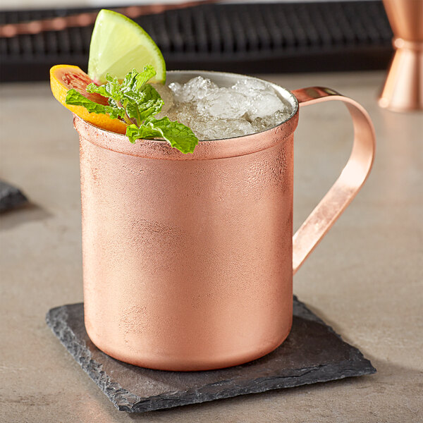 A copper Moscow Mule mug with ice and fruit garnish.