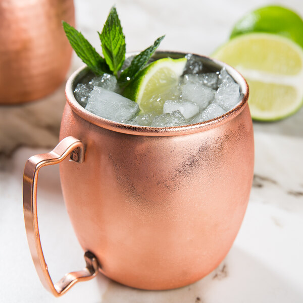 An Acopa Alchemy copper Moscow Mule mug filled with ice and limes.