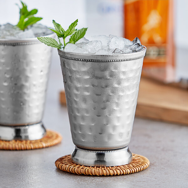 Two silver Acopa Alchemy mint julep cups filled with ice and mint leaves.