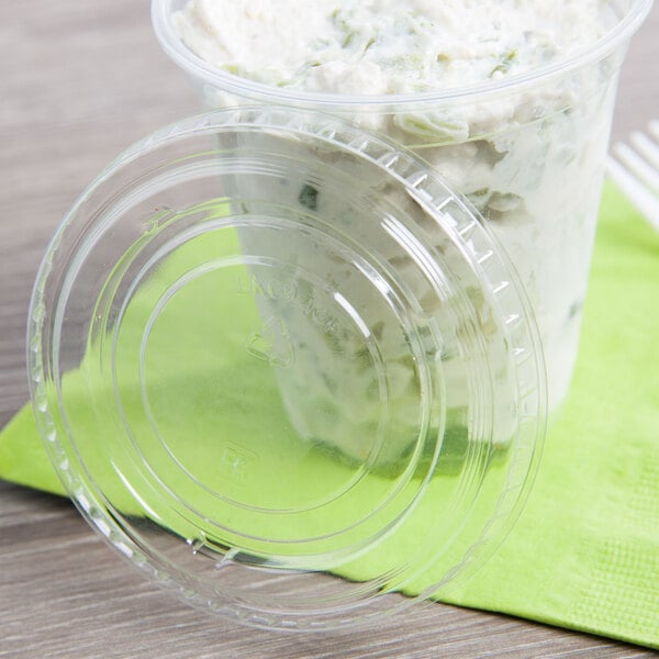 A Fabri-Kal clear plastic lid on a plastic cup with food in it.