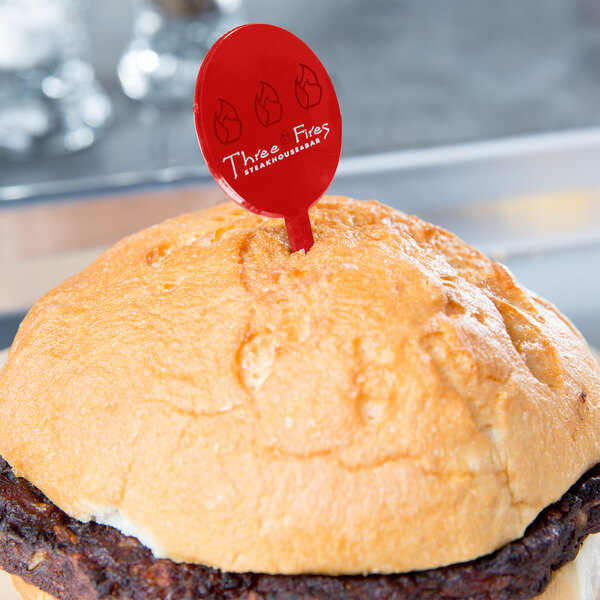 A hamburger with a red plastic sign on top.