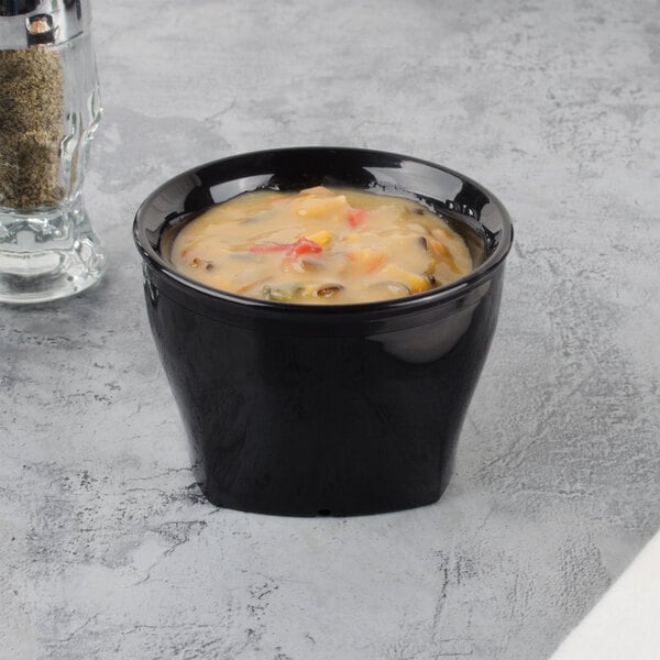 A black Cambro insulated plastic bowl of soup on a marbled surface.