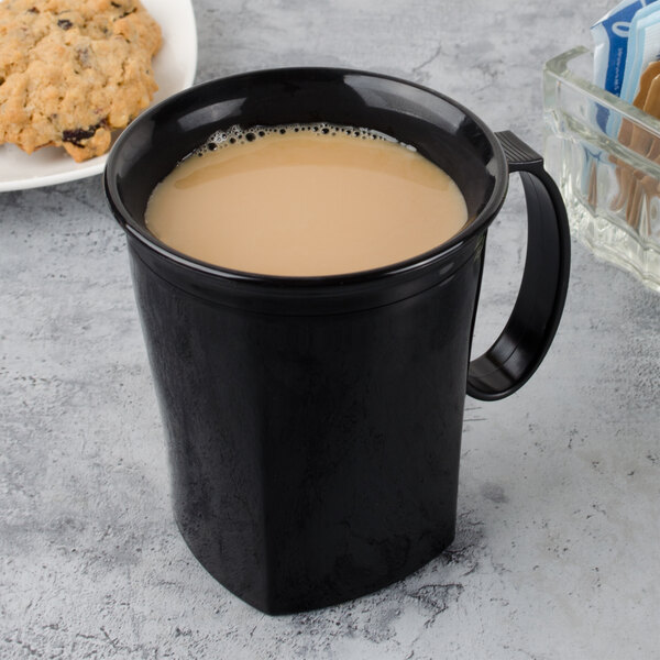 A black Cambro insulated mug filled with brown liquid next to cookies.
