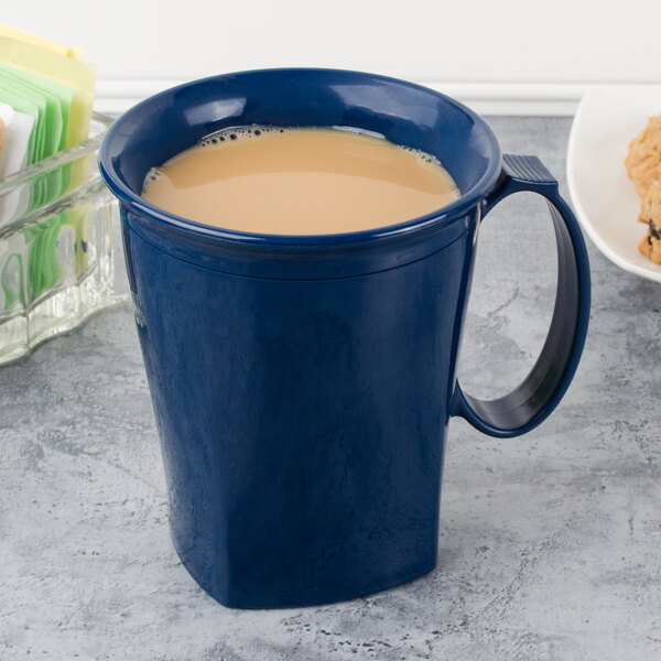 A navy blue Cambro insulated mug filled with a brown drink on a counter.