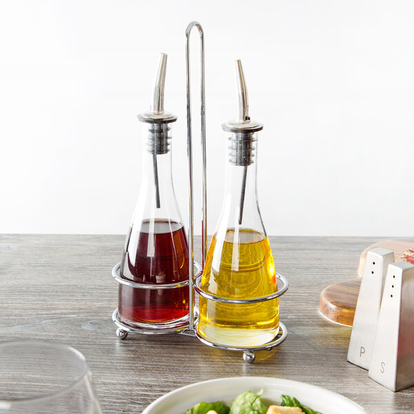 A Tablecraft Siena oil and vinegar cruet set on a table with oil and vinegar in glass bottles.