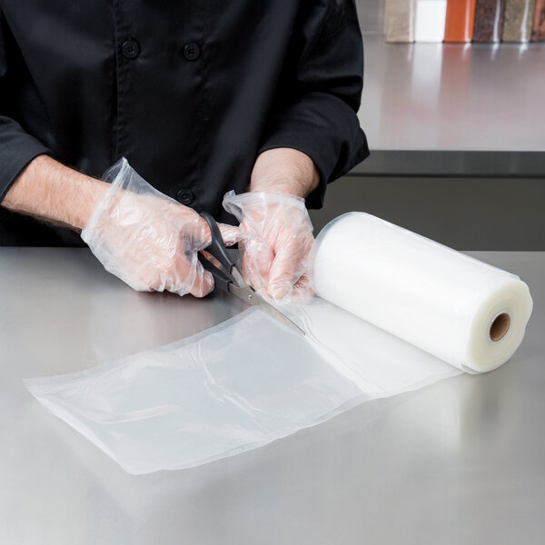 A person in a chef's uniform cutting an ARY VacMaster full mesh roll with scissors.