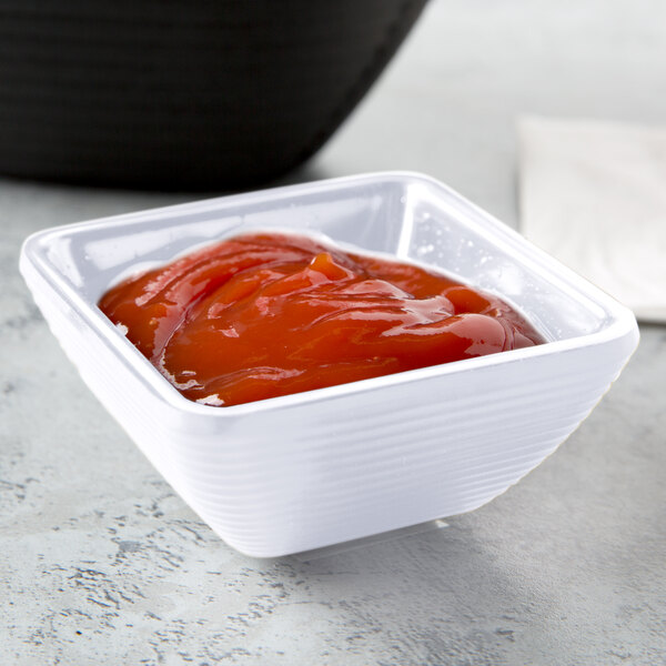 A white Tablecraft square ramekin filled with ketchup.