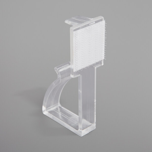 A clear plastic table skirt clip with a hook and loop attachment.