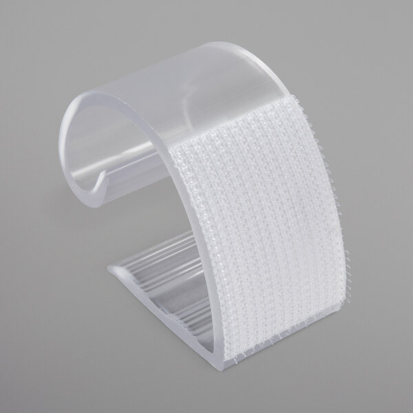 A clear plastic table skirt clip with a white plastic strip.