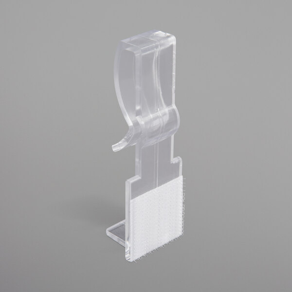 A clear plastic Snap Drape table skirt clip with white hook and loop strips.