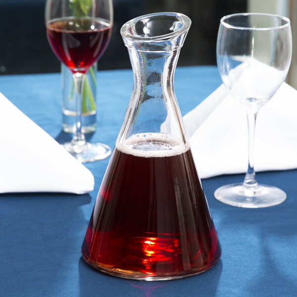 A Stolzle Pisa glass carafe filled with red wine on a table.