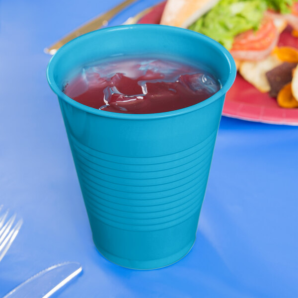 A turquoise blue plastic cup filled with a drink.