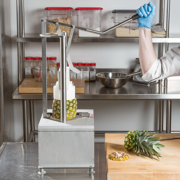 A person using a Tellier pineapple corer to press a pineapple.